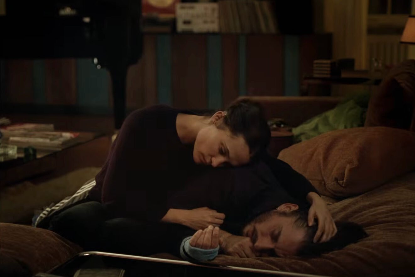 Anne e Leo abbracciati sul divano di Leo in una scena del film The Echo Chamber di Andrea Pallaoro